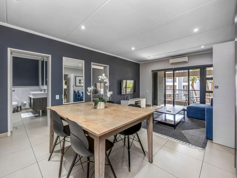 Modern open-plan living and dining area featuring tiled floors, recessed lighting, air conditioning, and direct access to a private balcony.