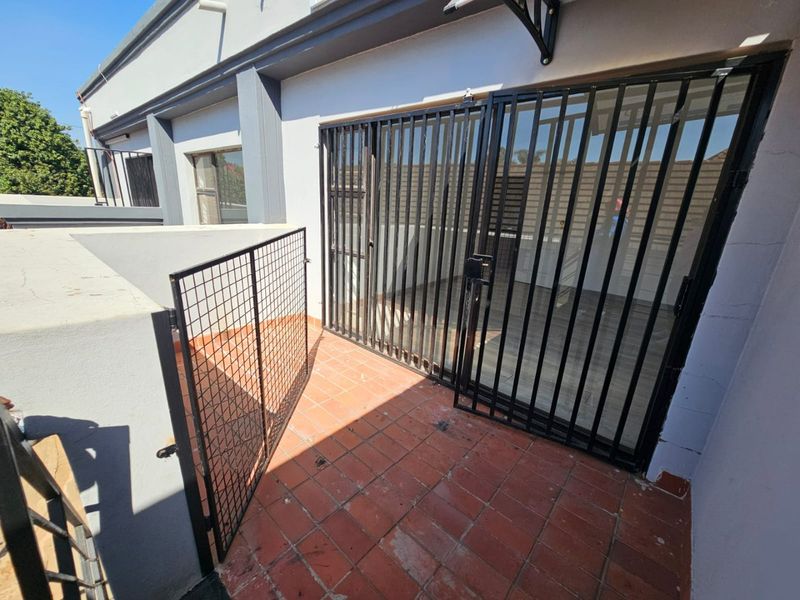 A private balcony area featuring terracotta-style floor tiles and a secure metal gate, providing an outdoor extension to the living space.