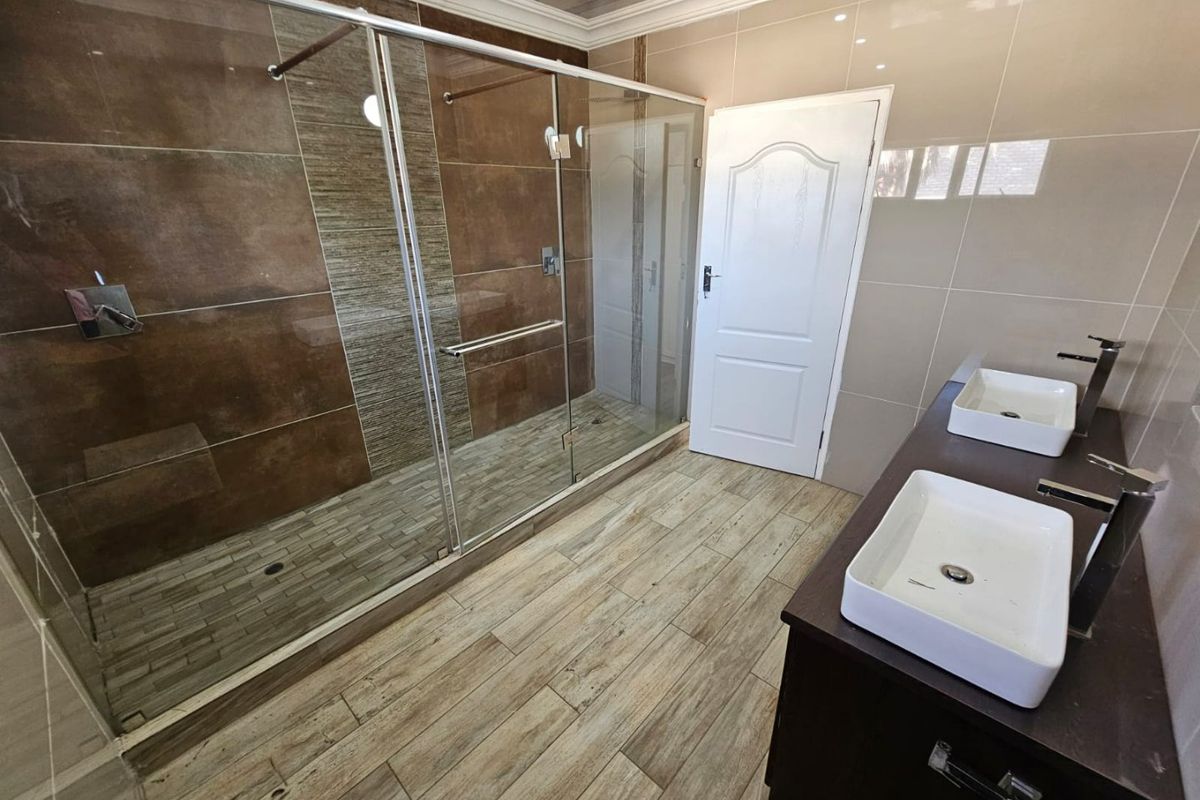 Modern bathroom featuring a spacious walk-in shower with glass enclosure, double vanity with vessel sinks, and contemporary tiled finishes.