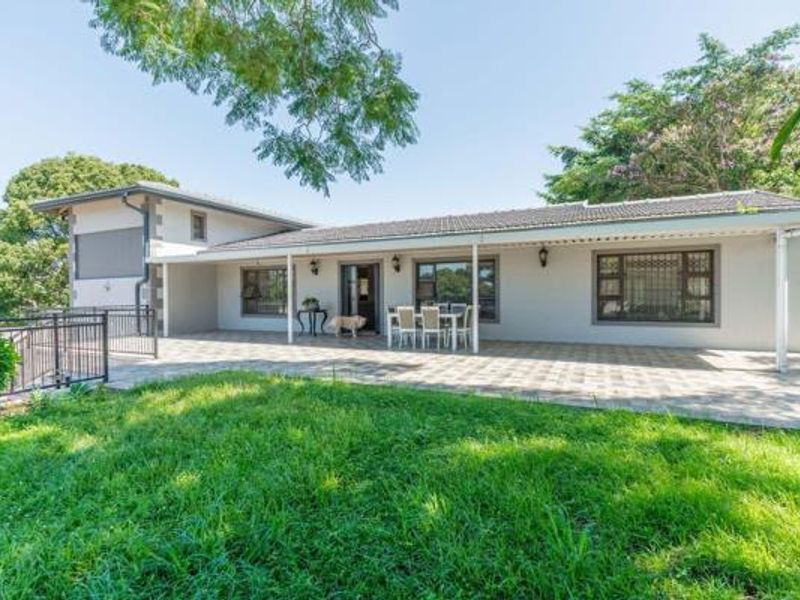 A spacious rear patio area featuring tiled flooring, security bars on windows, and direct access to the garden.