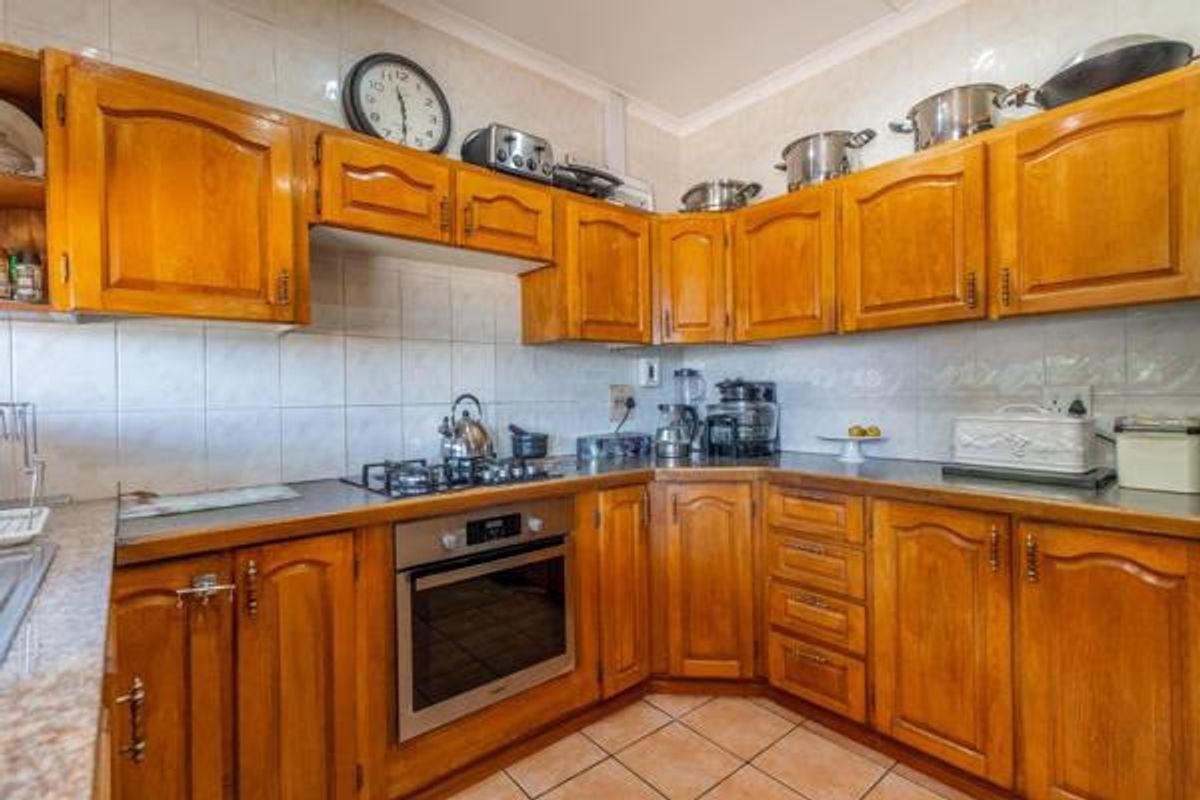A functional kitchen featuring traditional wooden cabinetry, a built-in oven, gas hob, and tiled finishes throughout.