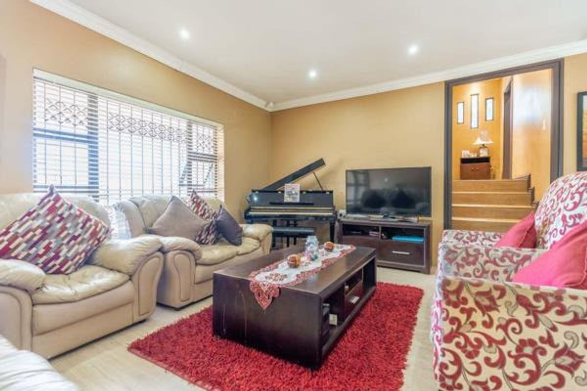 A comfortable living room featuring tiled flooring, recessed downlighting, and security bars on the windows, with an open transition to the staircase area.