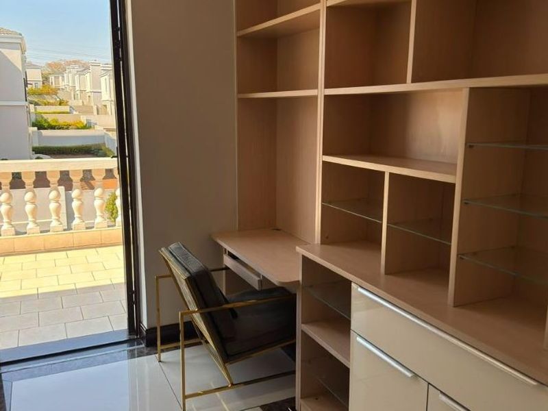 A functional home office featuring extensive built-in cabinetry, shelving, and direct access to an outdoor balcony area.