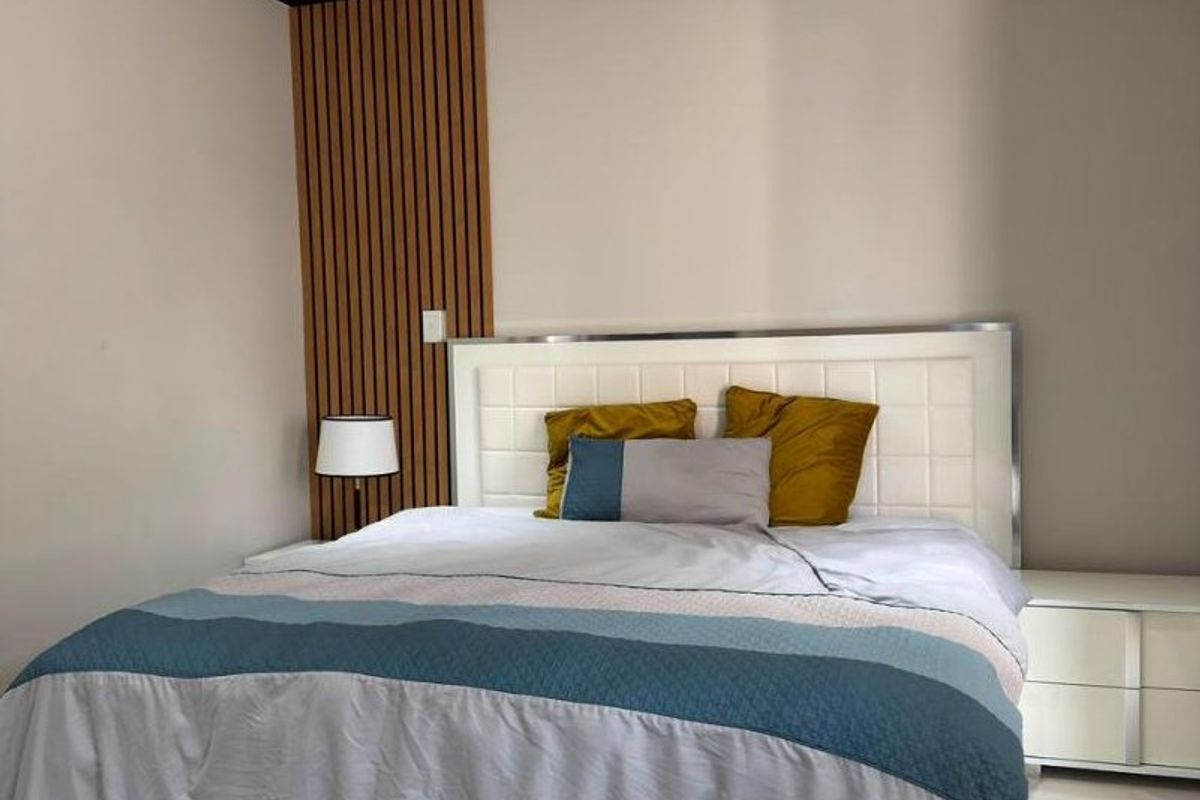 A modern bedroom featuring tiled flooring, recessed downlighting, and a decorative timber slat feature wall behind the bed area.