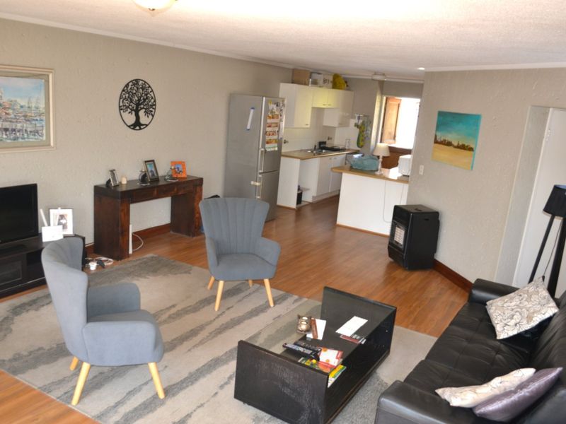 Open-plan living area featuring laminate flooring and a functional kitchen space with built-in cabinetry.