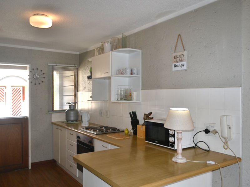 A functional kitchen featuring built-in cabinetry, laminate countertops, a gas hob, and a tiled backsplash, providing a practical workspace for daily cooking.