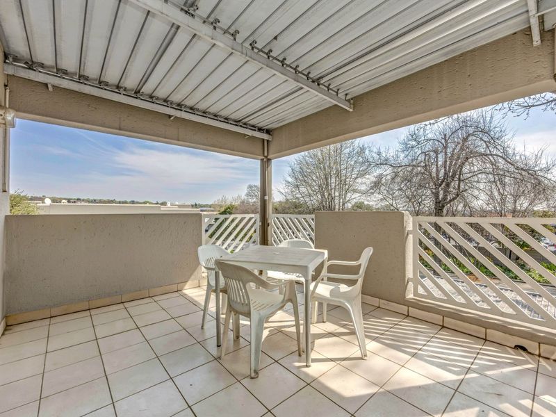 A covered balcony featuring tiled flooring and a lattice balustrade, offering an outdoor space suitable for relaxation.