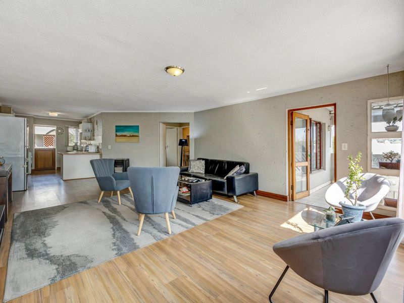 Open plan living area featuring laminate flooring, neutral walls, and direct access to an adjoining kitchen and outdoor patio space.
