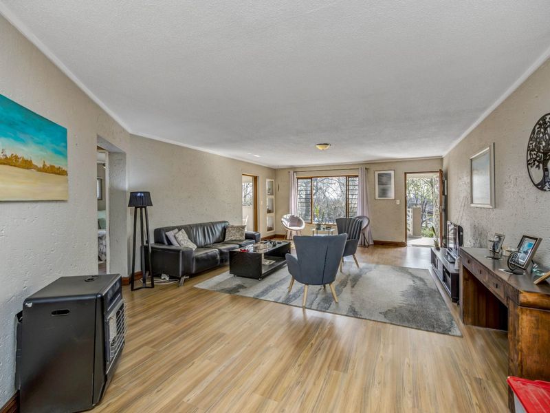 Spacious living room featuring laminate flooring, textured walls, and direct access to an outdoor area through a rear door.