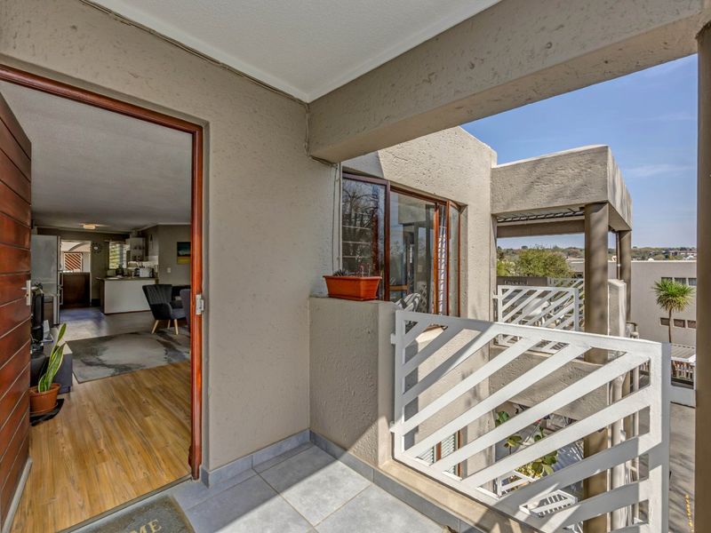 A covered balcony featuring tiled flooring and a white metal balustrade, providing an outdoor transition space from the interior living area.