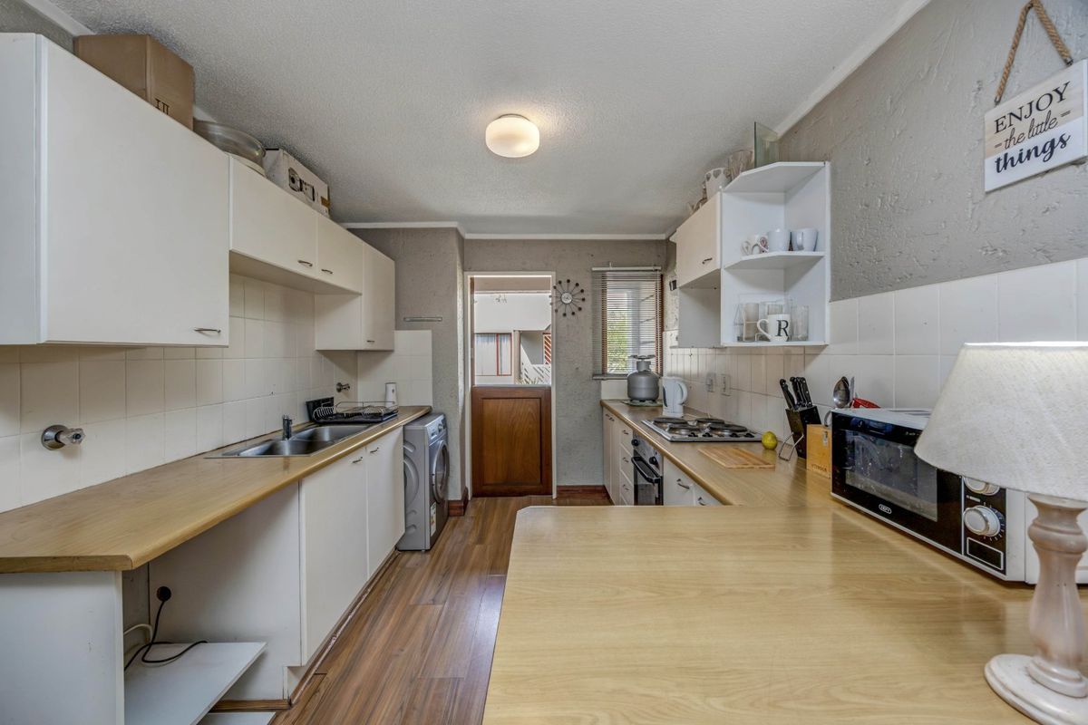 A functional kitchen featuring laminate countertops, built-in cabinetry, a gas hob, and a stable door leading to the exterior.