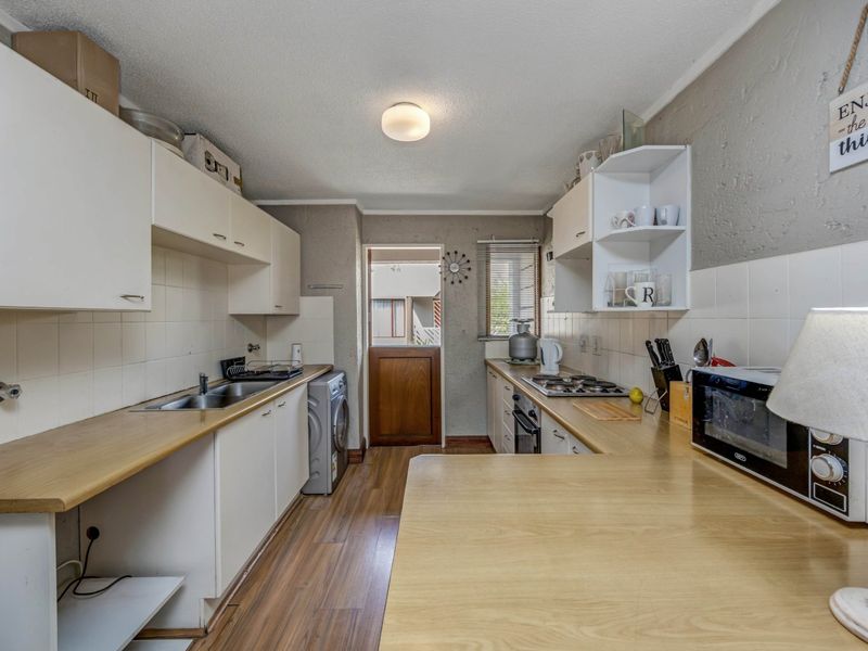 A functional kitchen featuring laminate countertops, built-in cabinetry, a gas hob, and a stable door leading to the exterior.