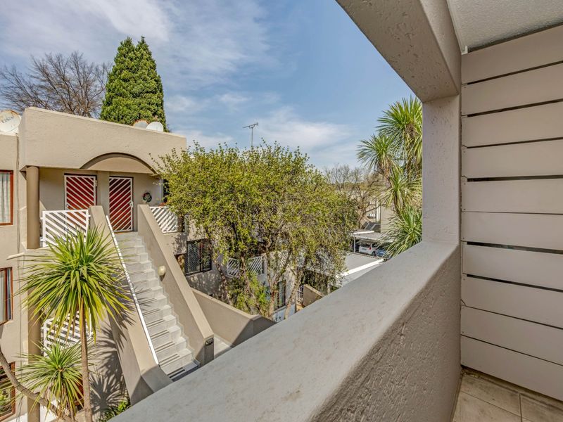 A view from a balcony overlooking the apartment complex courtyard, featuring exterior stairs and landscaped surroundings.