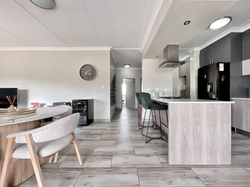 Modern open-plan living area featuring a contemporary kitchen with a central island, sleek cabinetry, and durable tiled flooring throughout the space.