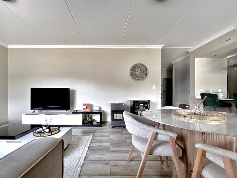 Spacious open-plan living and dining area featuring modern tiled flooring, neutral wall finishes, and a bright, functional layout suitable for contemporary apartment living.