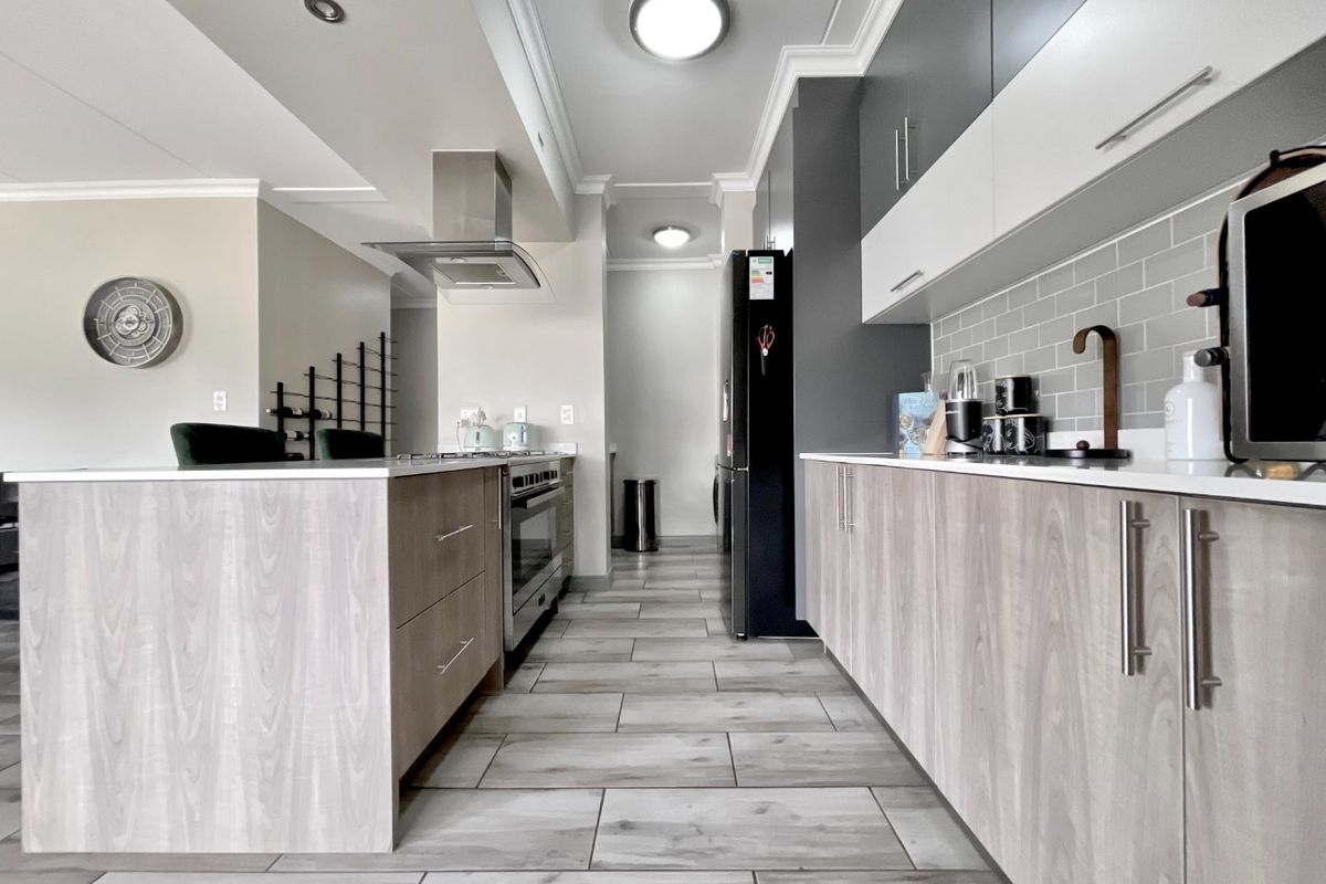 Modern kitchen featuring a central island, sleek cabinetry, subway tile backsplash, and high-end built-in appliances with contemporary finishes.