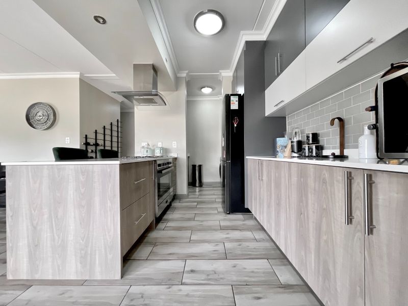 Modern kitchen featuring a central island, sleek cabinetry, subway tile backsplash, and high-end built-in appliances with contemporary finishes.
