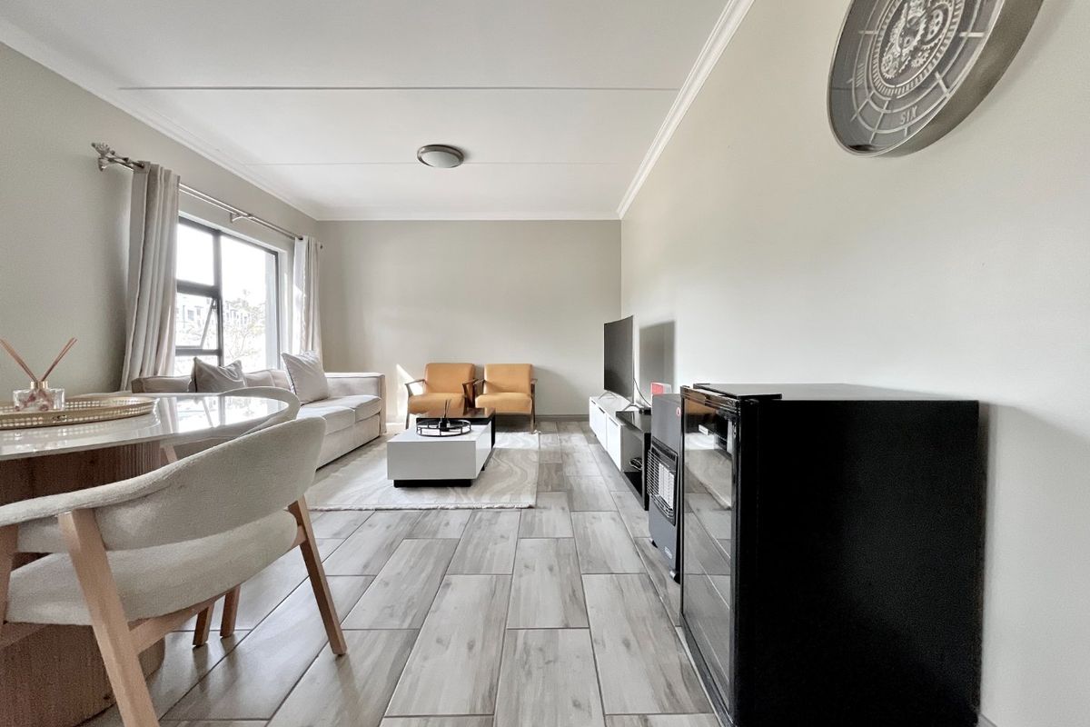 A bright and modern open-plan living area featuring contemporary wood-look tiled flooring and neutral wall finishes.