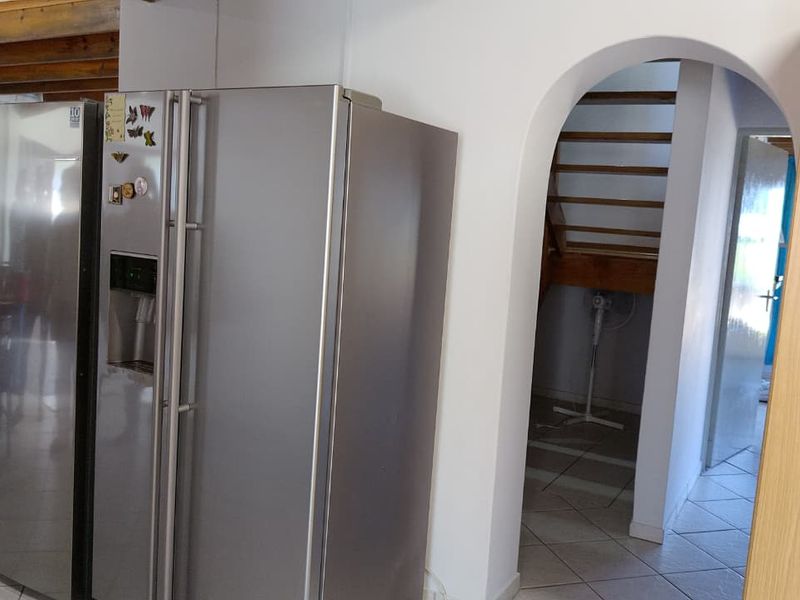 A kitchen area featuring an arched doorway leading to a staircase, with tiled flooring and exposed timber ceiling beams.