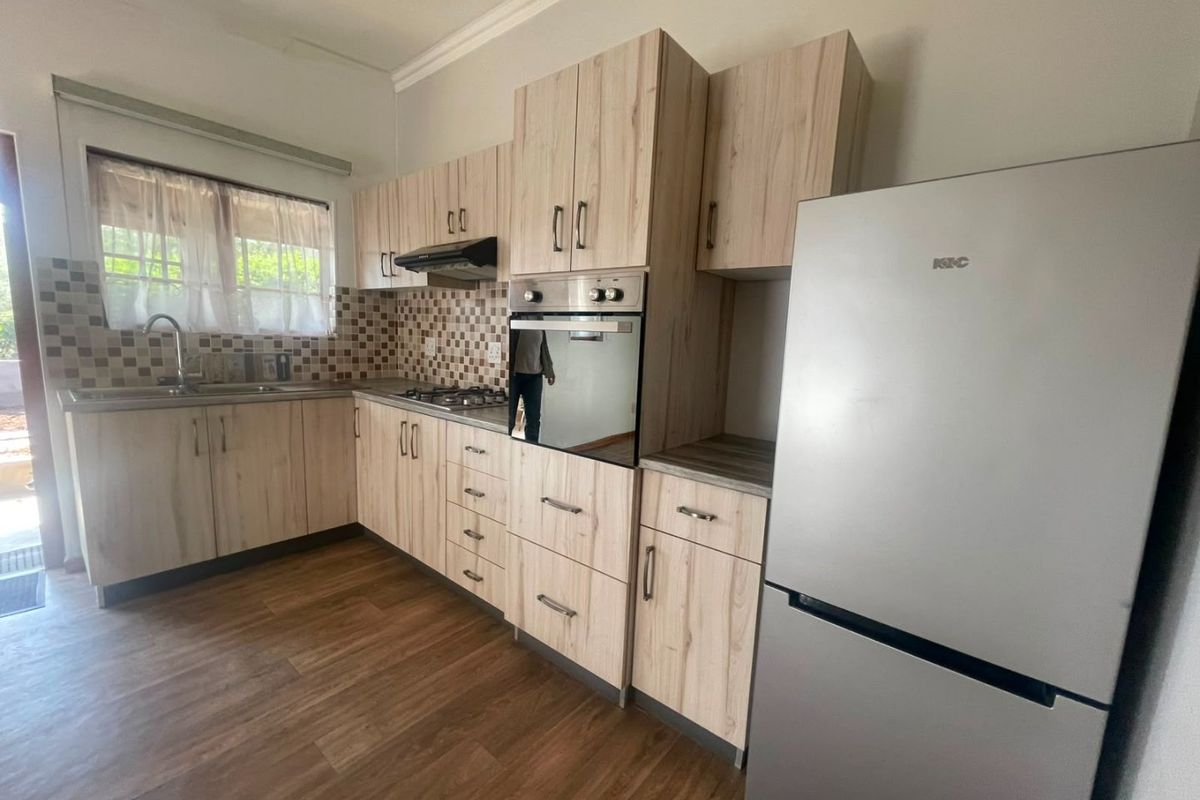A functional kitchen featuring light wood-grain cabinetry, laminate countertops, a built-in oven with gas hob, and a tiled backsplash.