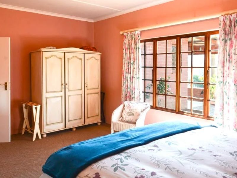 A bedroom featuring timber-framed windows and a built-in wardrobe, offering a functional space with natural light.