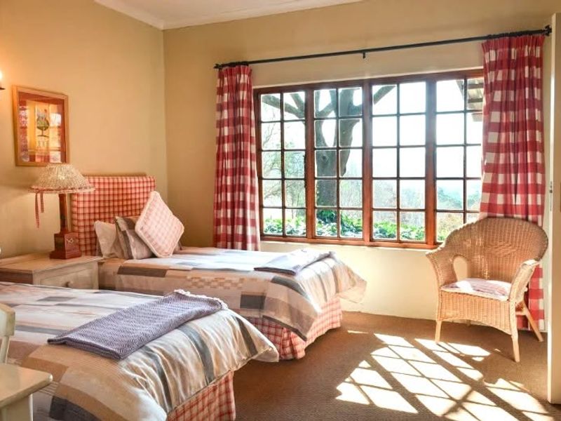 A cozy bedroom featuring timber-framed windows with natural light, carpeted flooring, and wall-mounted lighting.