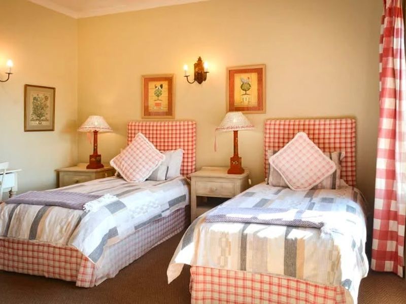 A twin bedroom featuring wall-mounted light fixtures and a window with checkered curtains.