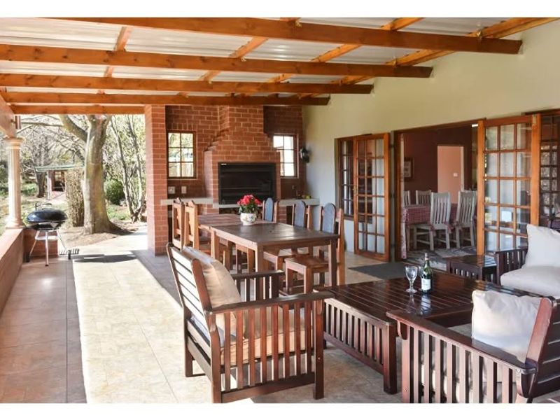 Spacious covered patio featuring a built-in brick fireplace, timber pergola roof, and tiled flooring, providing seamless indoor-outdoor flow through large french doors.