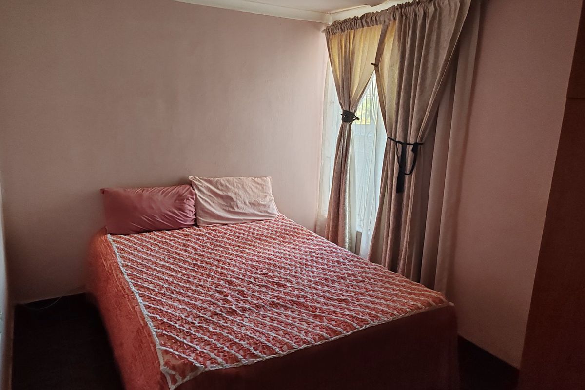 A standard bedroom featuring neutral wall finishes and a window with curtain fixtures.