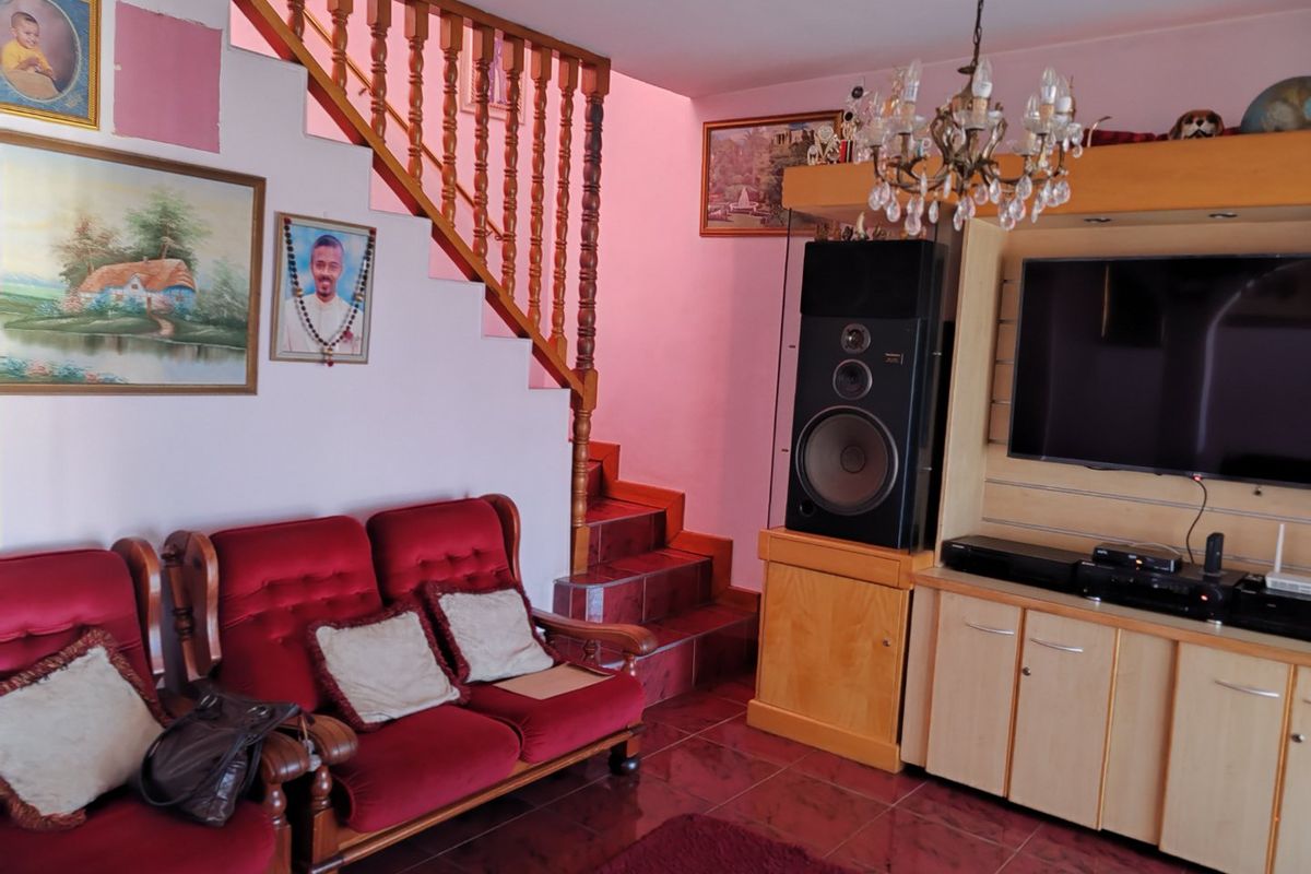 A living room featuring tiled flooring, a wooden staircase with a traditional balustrade, and built-in cabinetry for media storage.