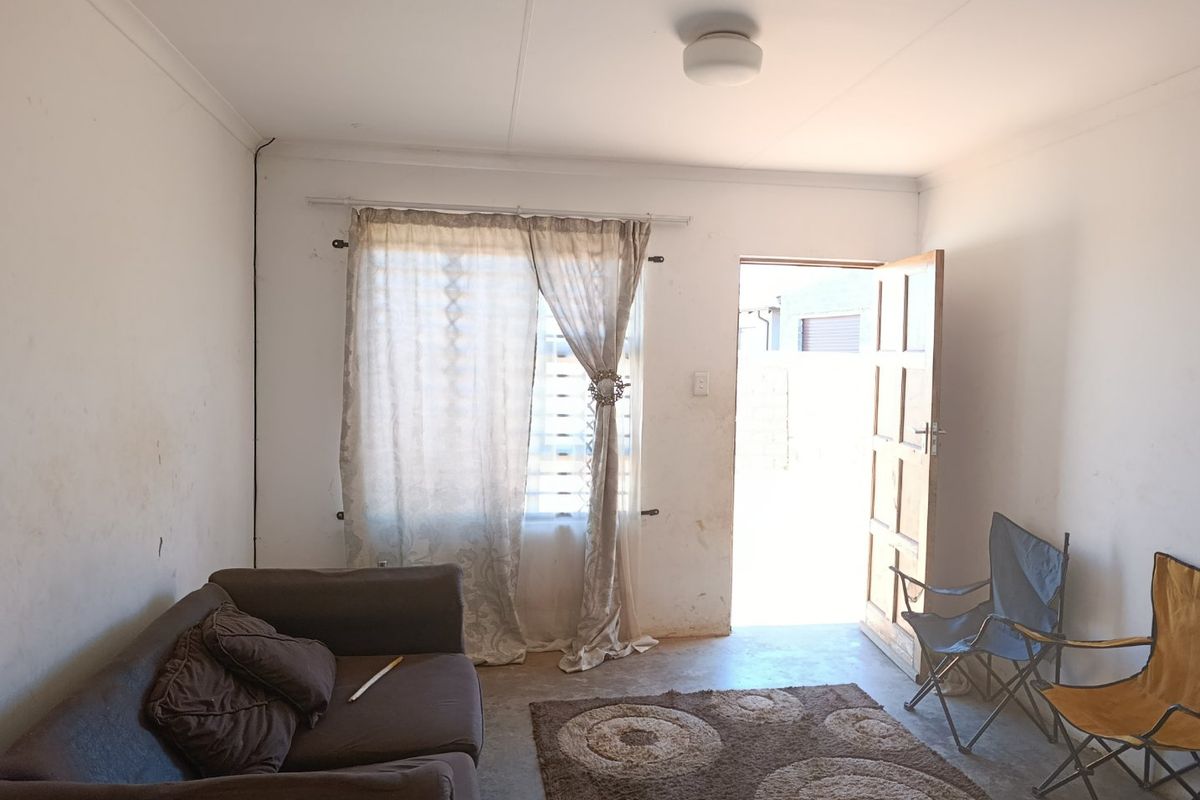 A living room area featuring a timber door leading to the exterior, a window with curtain fittings, and a central ceiling light fixture.