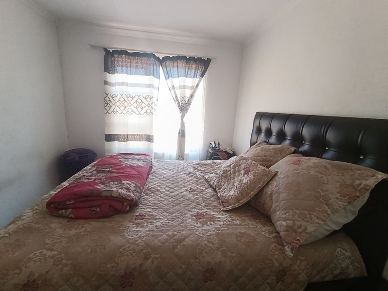 A standard bedroom featuring a window with a fitted curtain rod, providing natural light to the space.