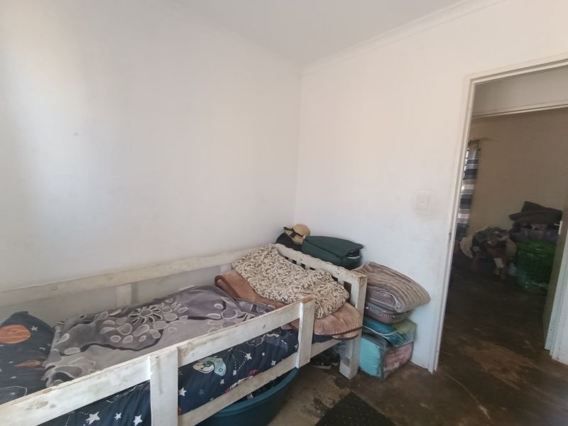 A simple bedroom space featuring plain walls and basic flooring, offering a blank canvas for potential renovation or interior design updates.