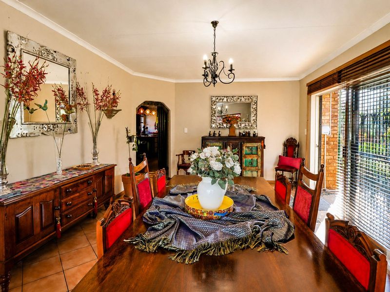 A traditional dining room featuring tiled flooring, a wrought iron chandelier, and direct access to an outdoor patio area through sliding glass doors.