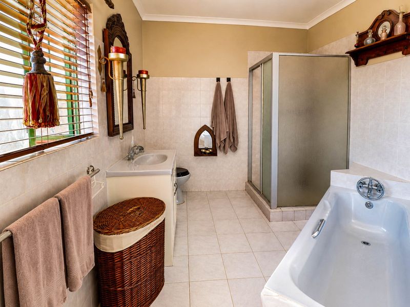 A functional bathroom featuring a bathtub, separate shower enclosure, and a vanity basin with tiled finishes throughout.