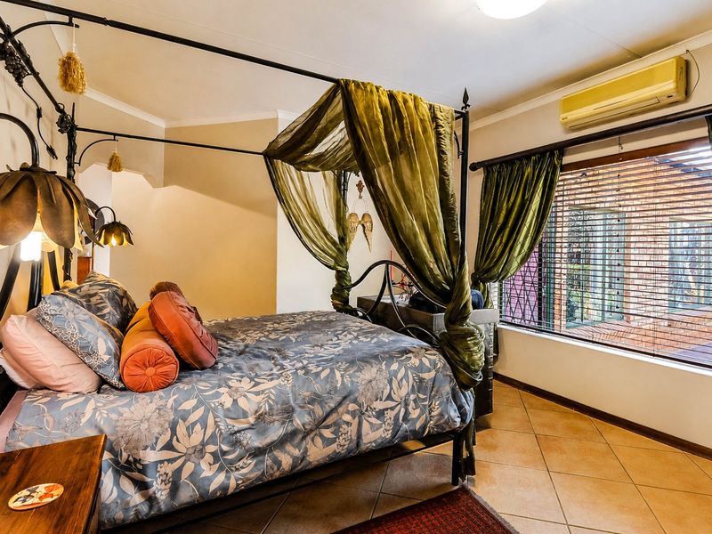 A bedroom featuring tiled flooring, a wall-mounted split-system air conditioner, and windows fitted with security bars and blinds.