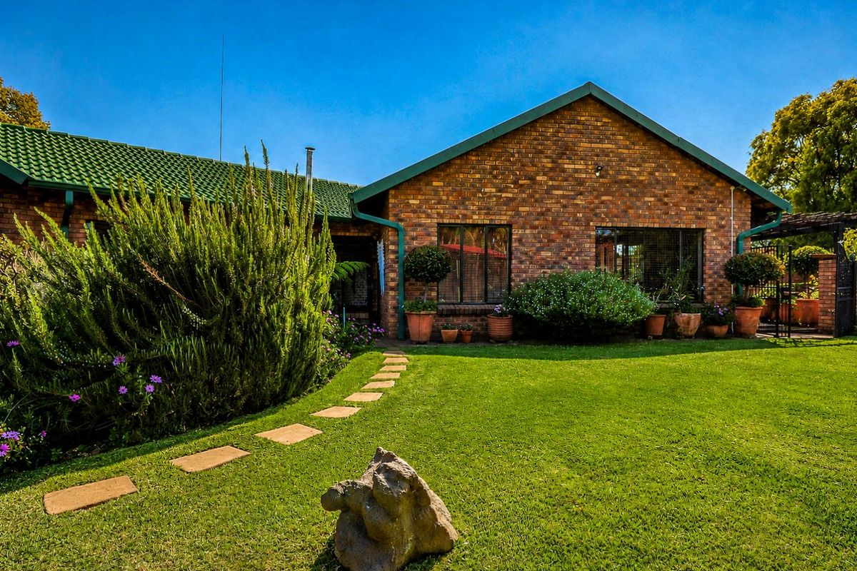 A well-maintained rear exterior view of a face brick house featuring a green tiled roof, a manicured lawn, and a stone pathway.