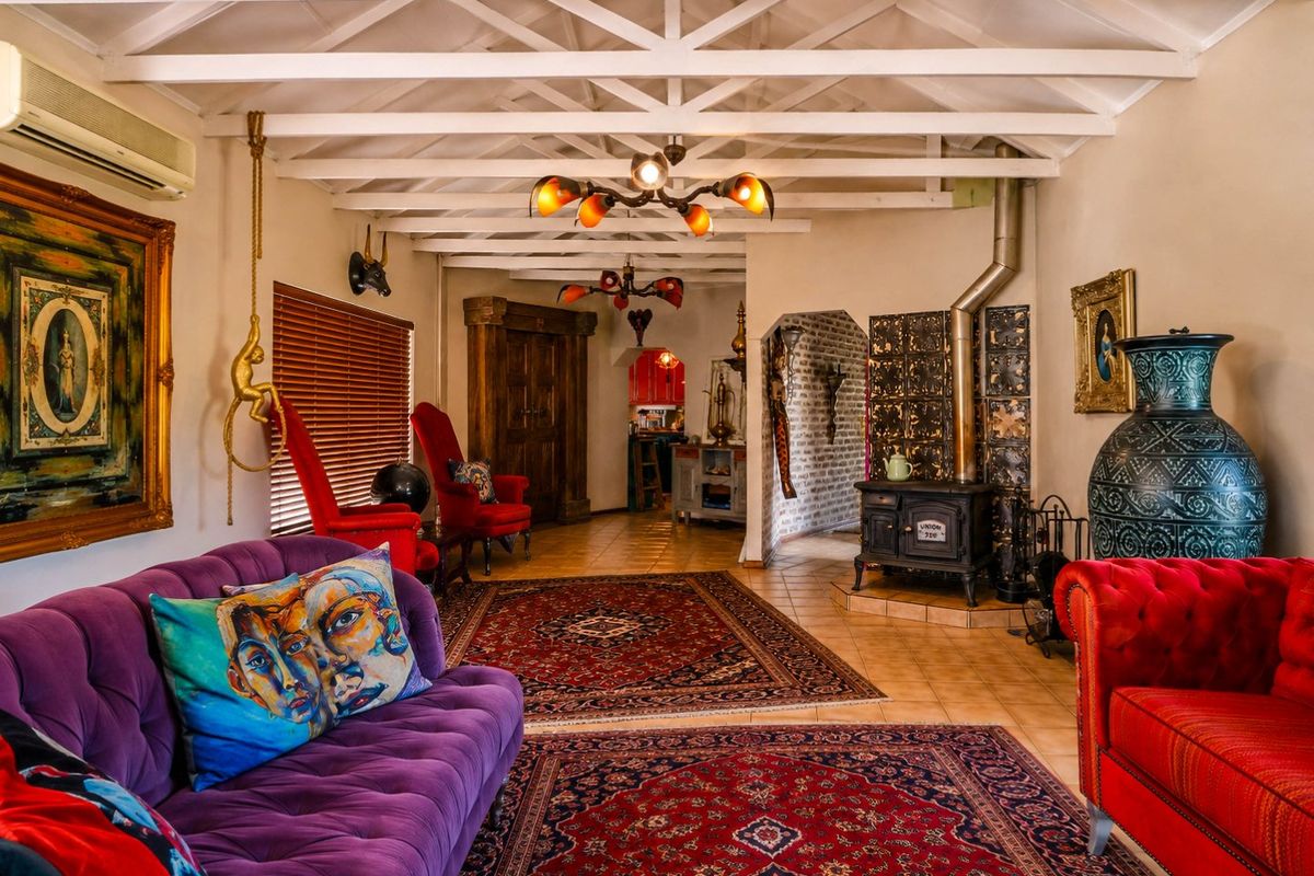 Spacious living room featuring exposed timber ceiling beams, a classic cast iron wood-burning stove, and tiled flooring with a view into the kitchen area.