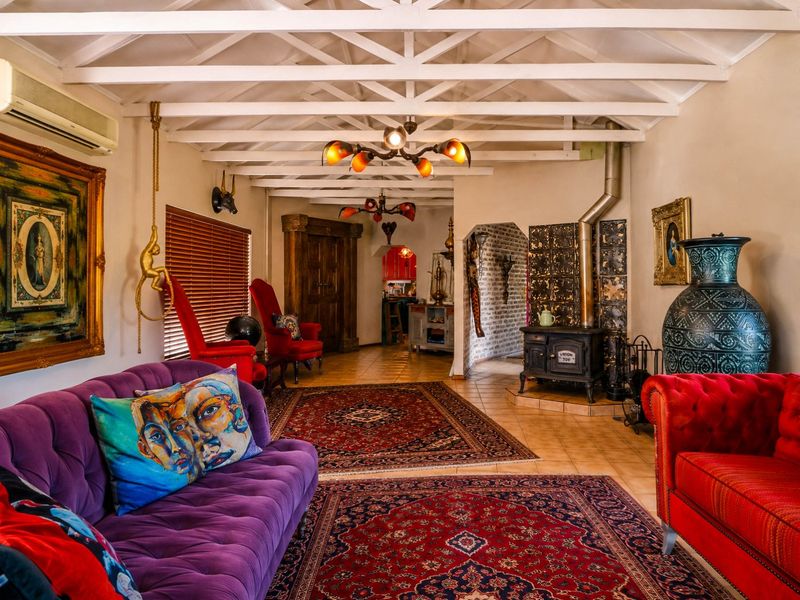 Spacious living room featuring exposed timber ceiling beams, a classic cast iron wood-burning stove, and tiled flooring with a view into the kitchen area.