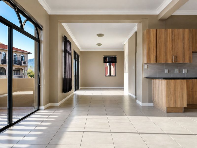 Spacious open-plan living area featuring tiled floors, modern wood-finish kitchen cabinetry, and large sliding glass doors leading to an outdoor balcony.