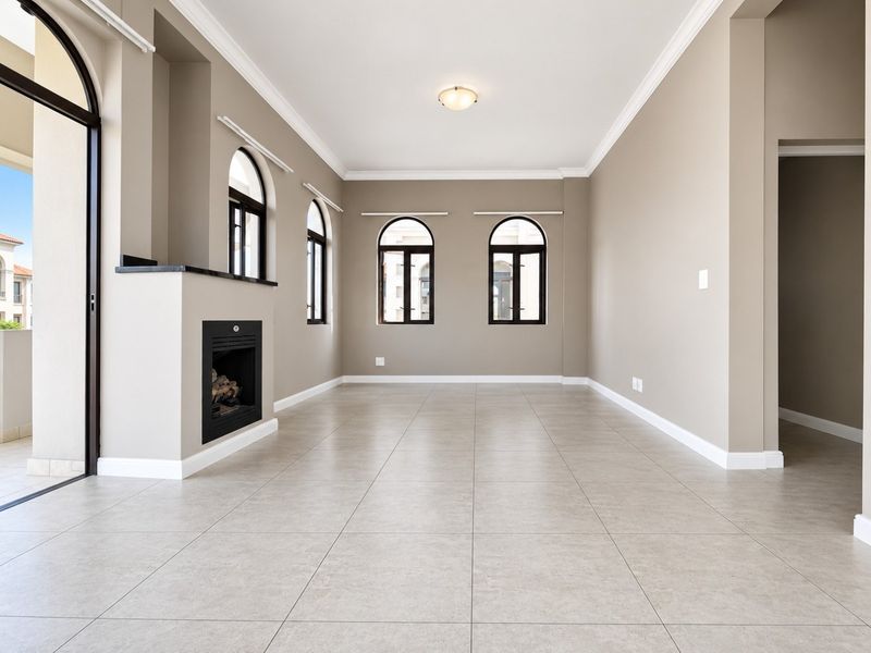 Spacious living room featuring neutral tiled flooring, a built-in fireplace, elegant arched windows, and direct access to an outdoor patio area.