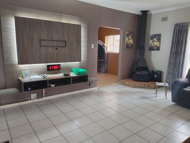 Spacious living room featuring a built-in media unit with integrated lighting, tiled flooring, and a prominent freestanding fireplace.