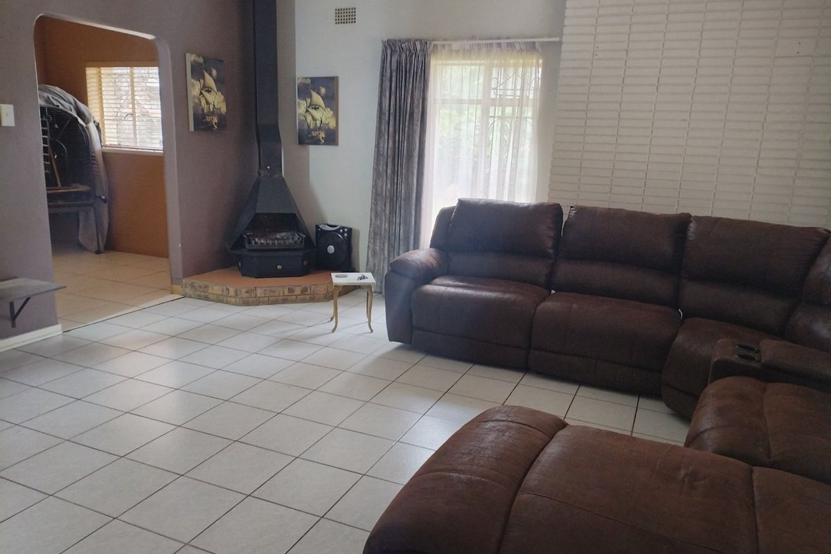 Spacious living room featuring tiled flooring, a prominent freestanding fireplace with a brick surround, and an arched entryway leading to an adjacent room.