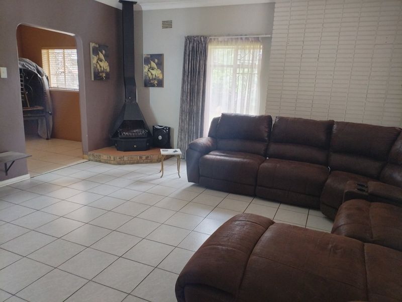 Spacious living room featuring tiled flooring, a prominent freestanding fireplace with a brick surround, and an arched entryway leading to an adjacent room.