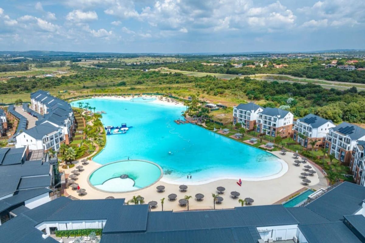 Aerial view of a large residential apartment complex featuring a expansive central swimming lagoon and landscaped communal outdoor areas.