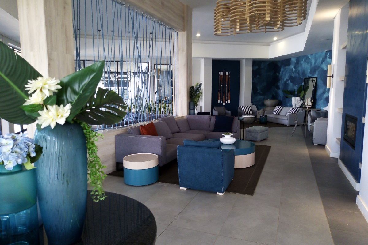 A spacious and modern living area featuring large format floor tiles, a built-in fireplace, and a unique decorative ceiling fixture.