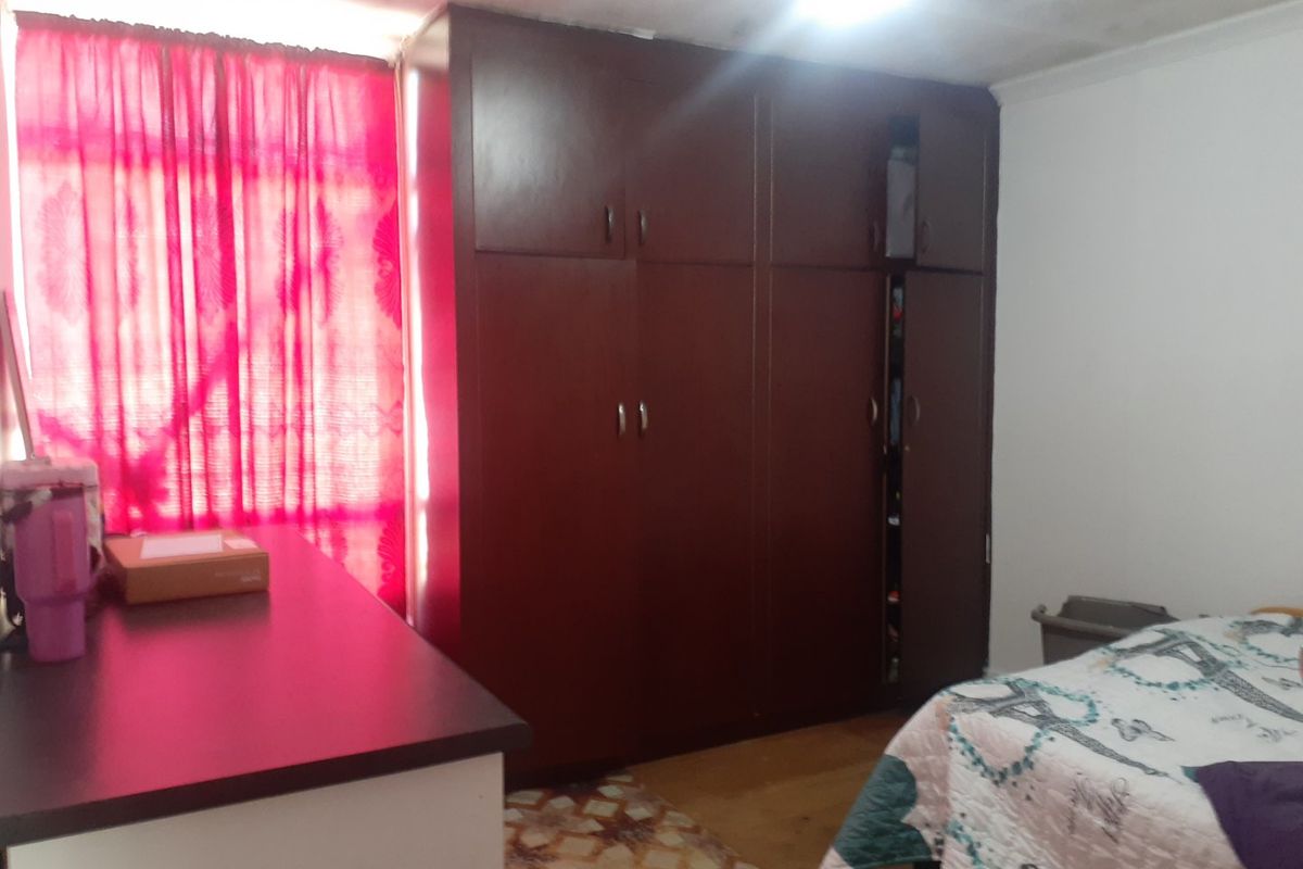 A bedroom featuring a large built-in wardrobe and visible ceiling staining, requiring maintenance and cosmetic updates.