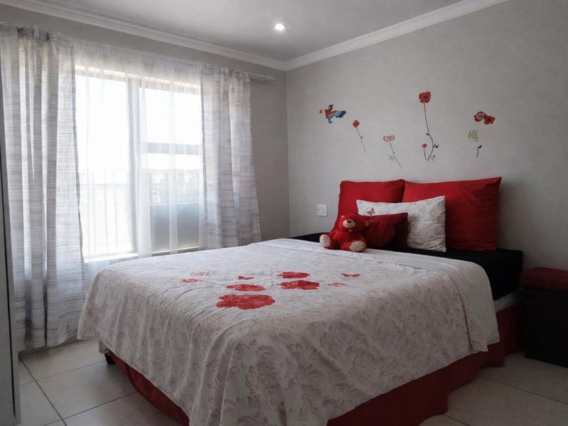 A well-maintained bedroom featuring tiled flooring, recessed downlighting, and a large sliding window with curtain tracks.