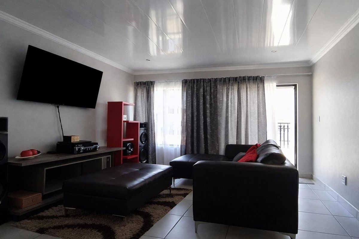 A well-maintained living room featuring tiled flooring, crown molding, and direct access to an outdoor area through a sliding door.