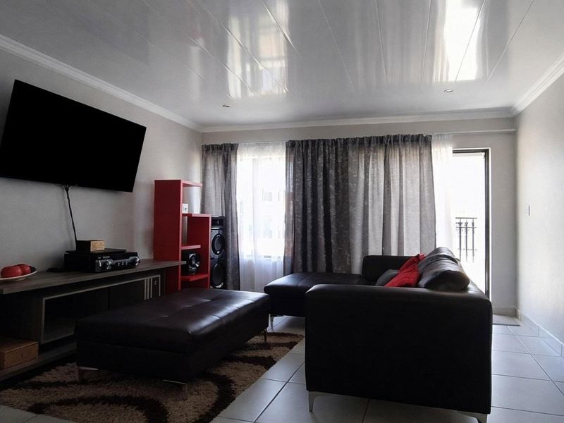 A well-maintained living room featuring tiled flooring, crown molding, and direct access to an outdoor area through a sliding door.